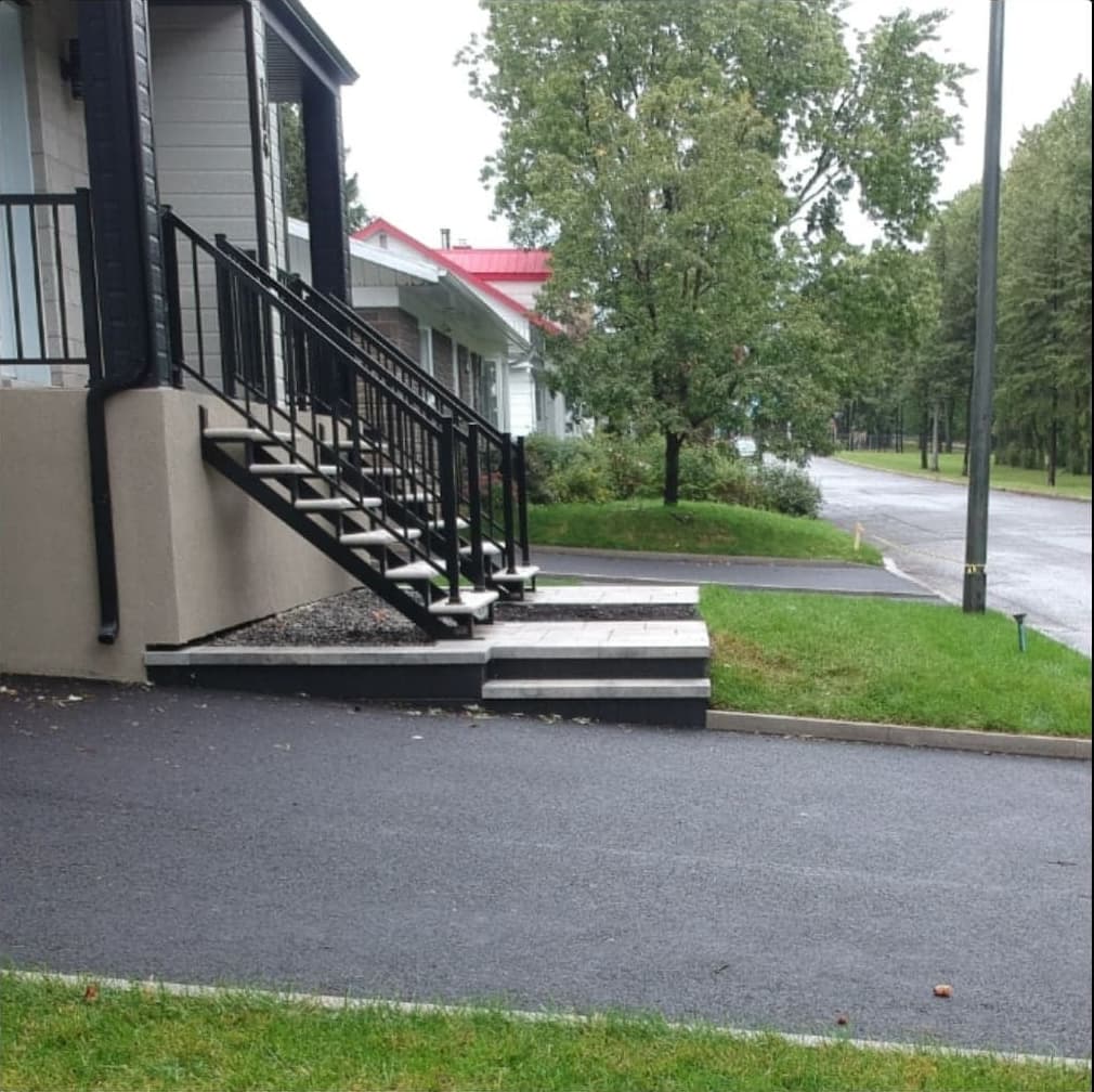Après les travaux — entrée asphaltée avec escalier métallique, marches en dalles et pelouse