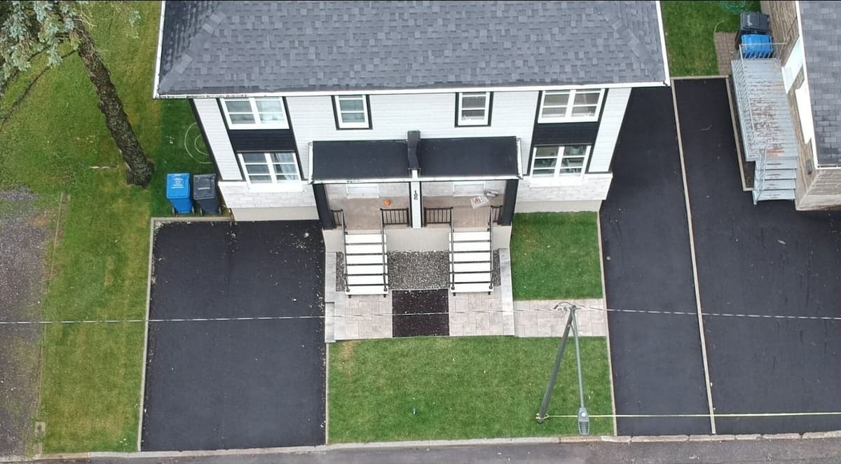 Après les travaux — vue aérienne d’un duplex avec entrées asphaltées, allées en dalles et pelouse