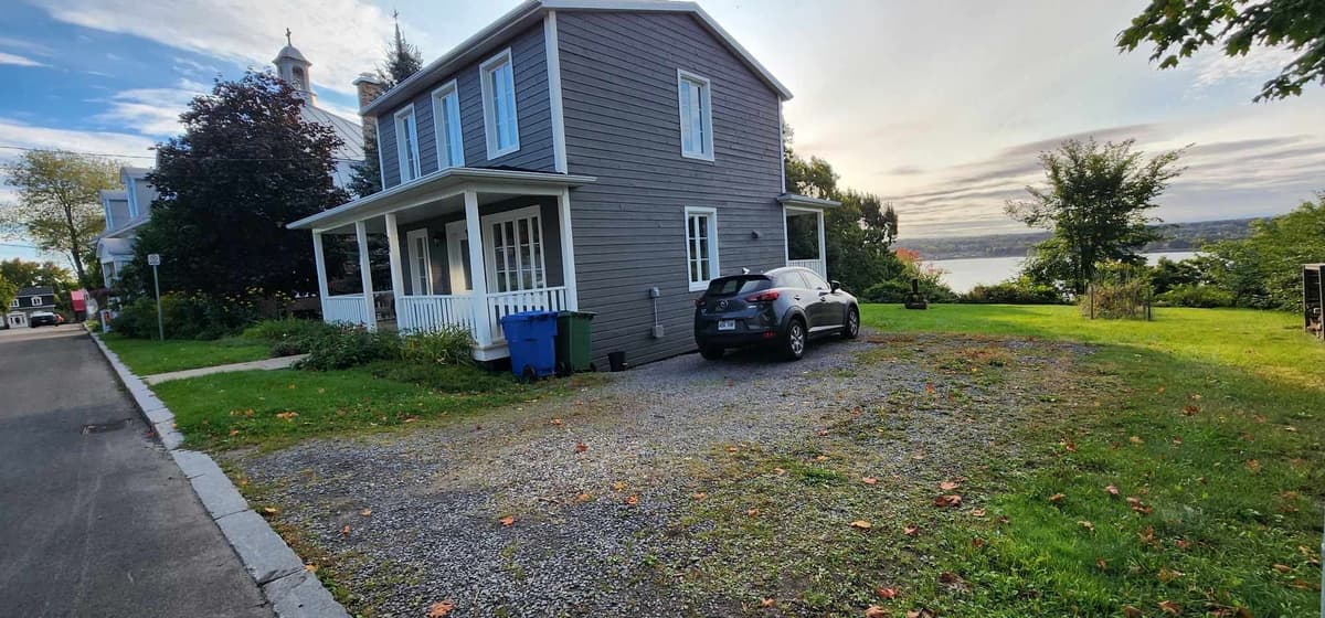 Avant les travaux — stationnement en gravier devant une maison au bord du fleuve à Sainte-Foy