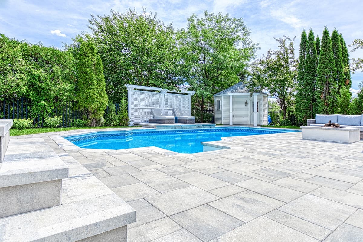Après les travaux — contour de piscine entièrement aménagé en pavé, avec larges espaces de détente, marches et mobilier extérieur