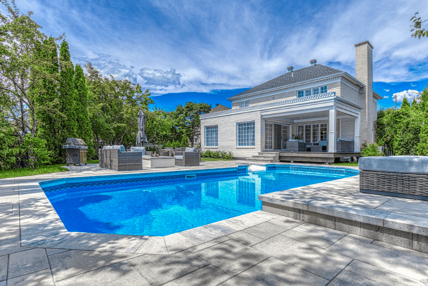 Après les travaux — contour de piscine entièrement aménagé en pavé, avec marches, espaces de détente et mobilier extérieur