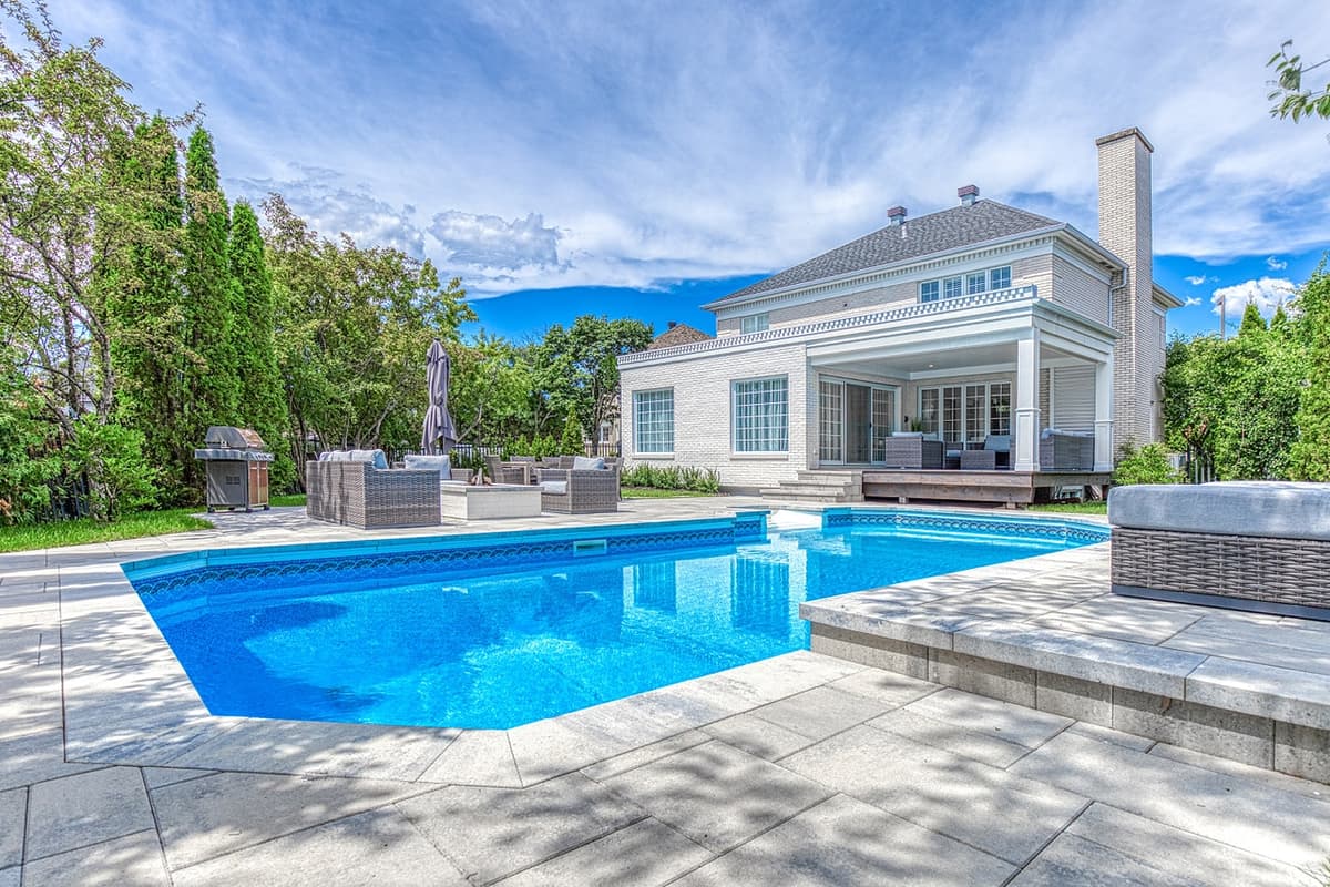 Après les travaux — contour de piscine entièrement aménagé en pavé, avec marches, espaces de détente et mobilier extérieur