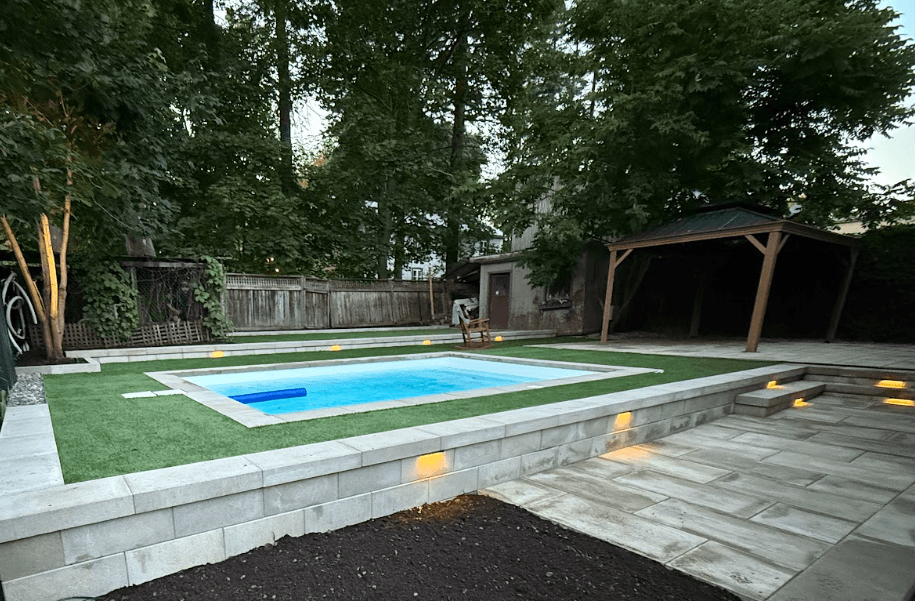 Après les travaux — piscine surélevée avec contour en dalles, gazon, muret éclairé et gazebo à Charlesbourg